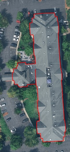 Vertical aerial of the Hilton Garden Inn Portland-Beaverton with the building footprint outlined in red against the surface parking and tree-lined site